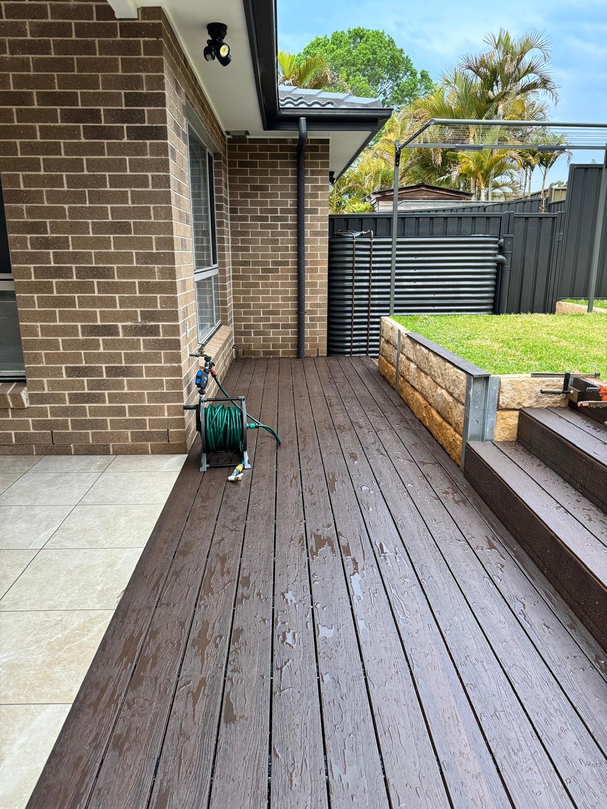 Composite timber deck alongside sandstone retaining wall and lawn