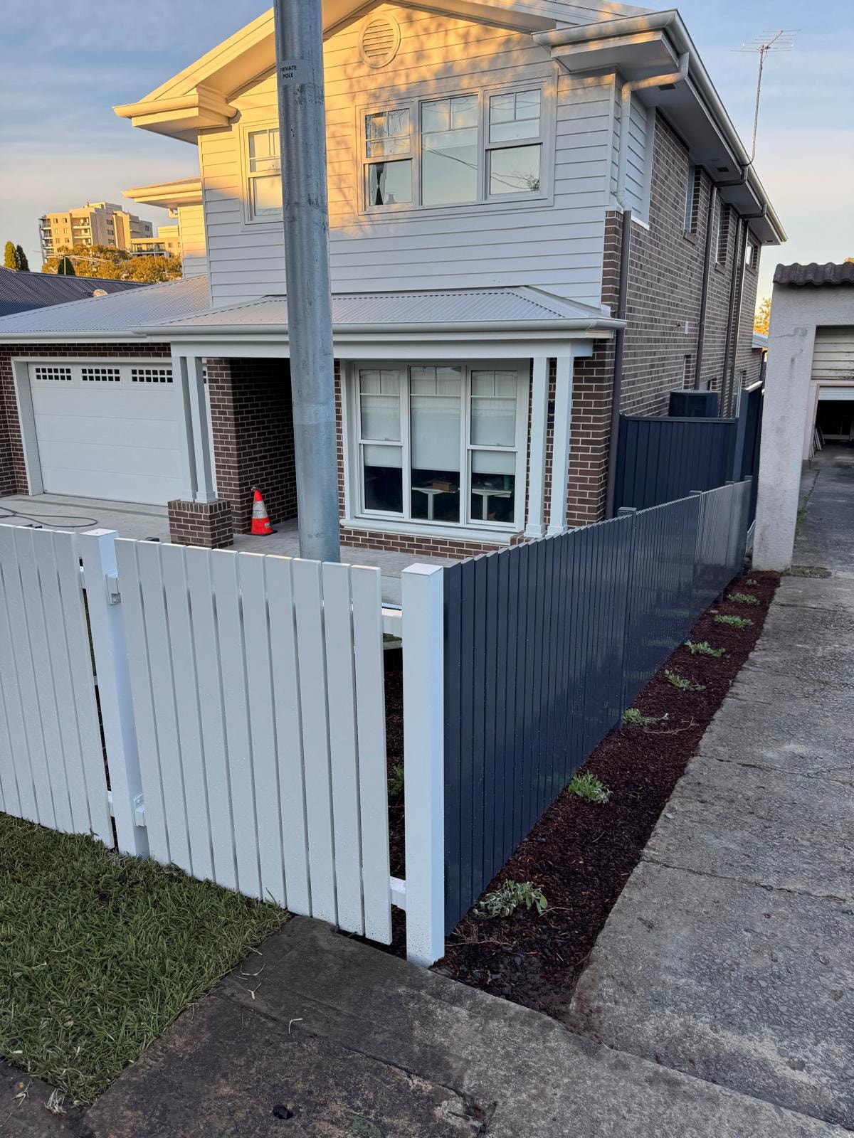 Residential brick home with new white and charcoal fencing and garden bed