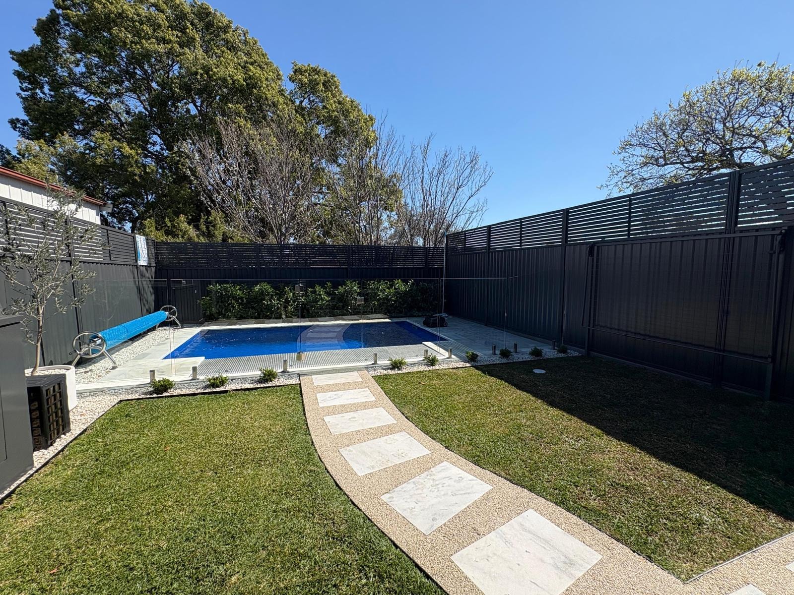 Backyard pool with curved marble stepping stone path through lawn