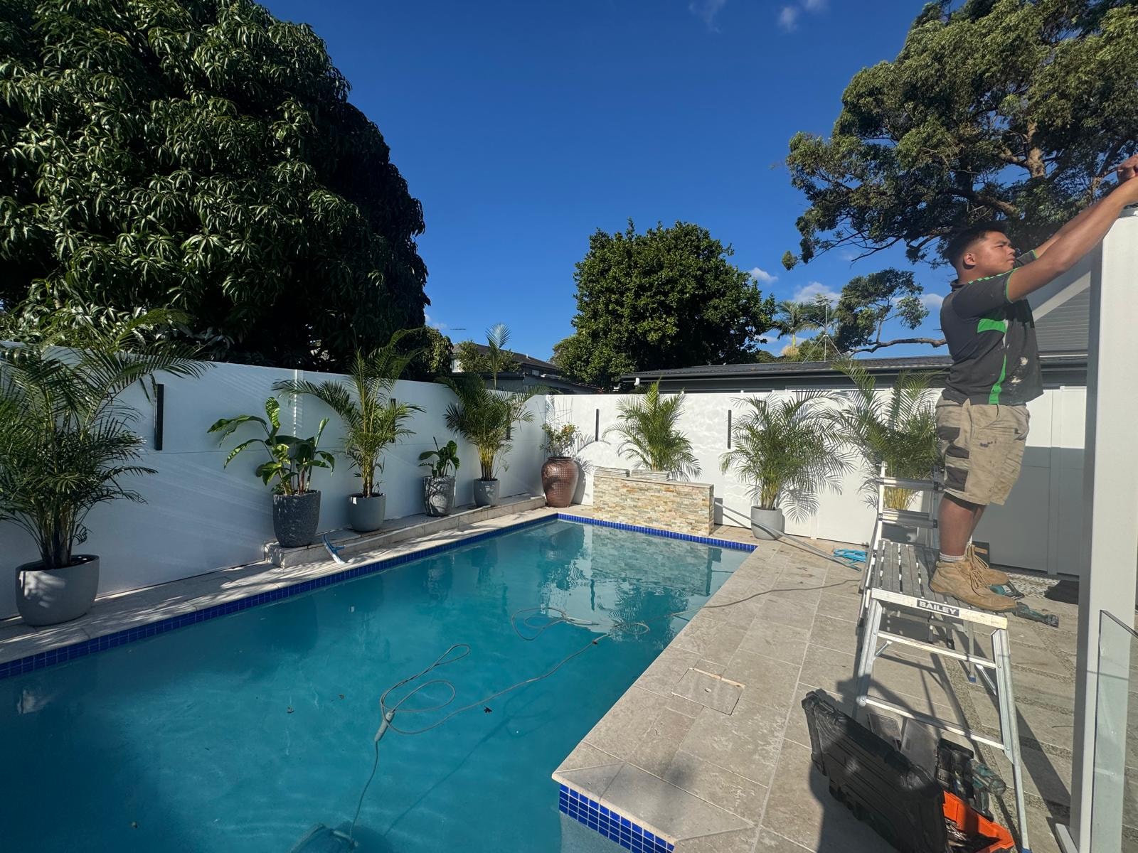 GPC Landscapes team member installing pool surrounds with potted palms