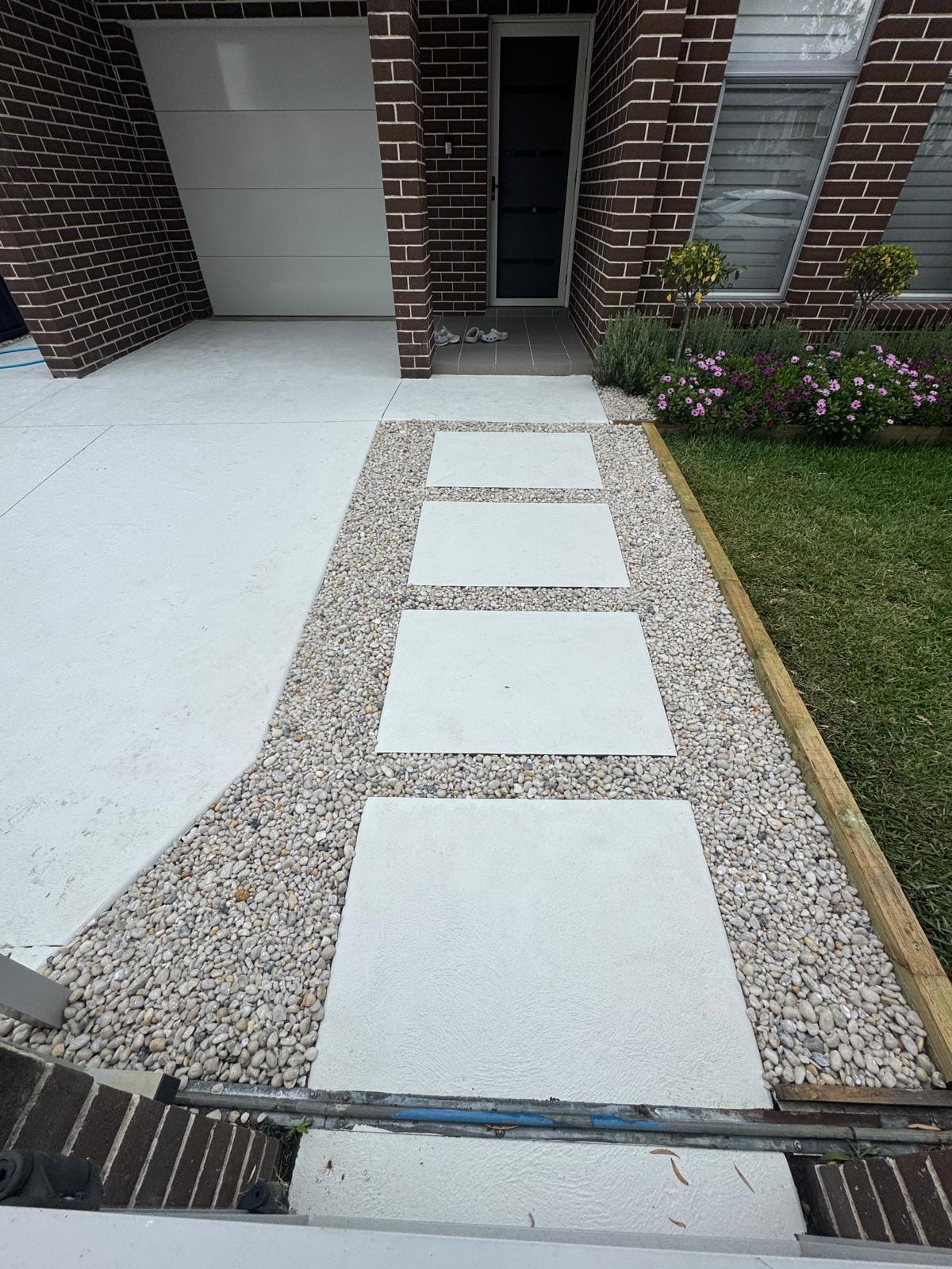 White porcelain stepping stones through white pebble path with garden bed and flowers