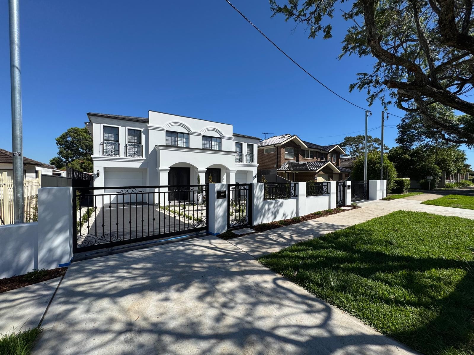 White rendered home with ornate iron gate and landscaped entrance
