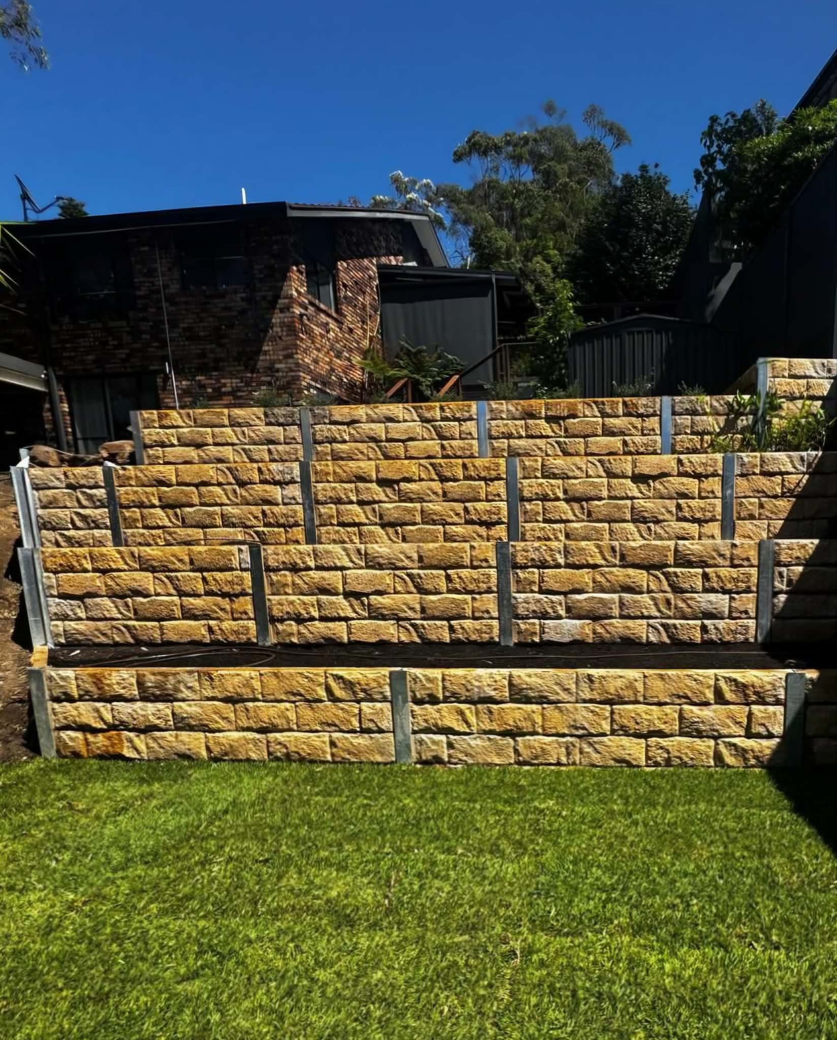 Completed sandstone block retaining wall with fresh lawn